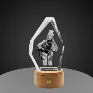 An iceberg-shaped crystal featuring a 3D laser engraving of a girl in a beanie holding a black pug, set on a round wooden rotating LED base against a gray gradient background.