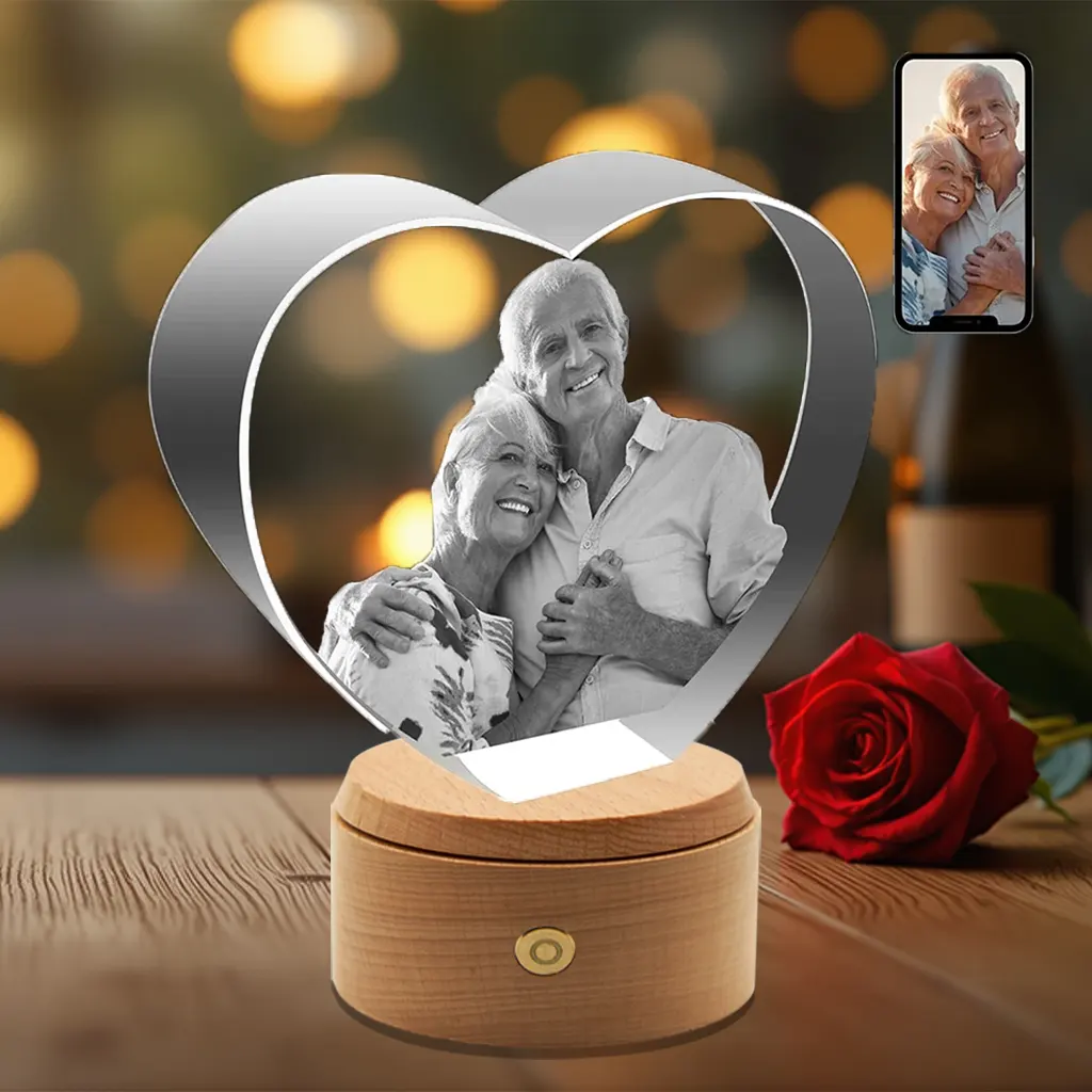 A custom heart-shaped 3D crystal photo for an anniversary, featuring an engraved portrait of an elderly couple on a rotating LED wooden base.