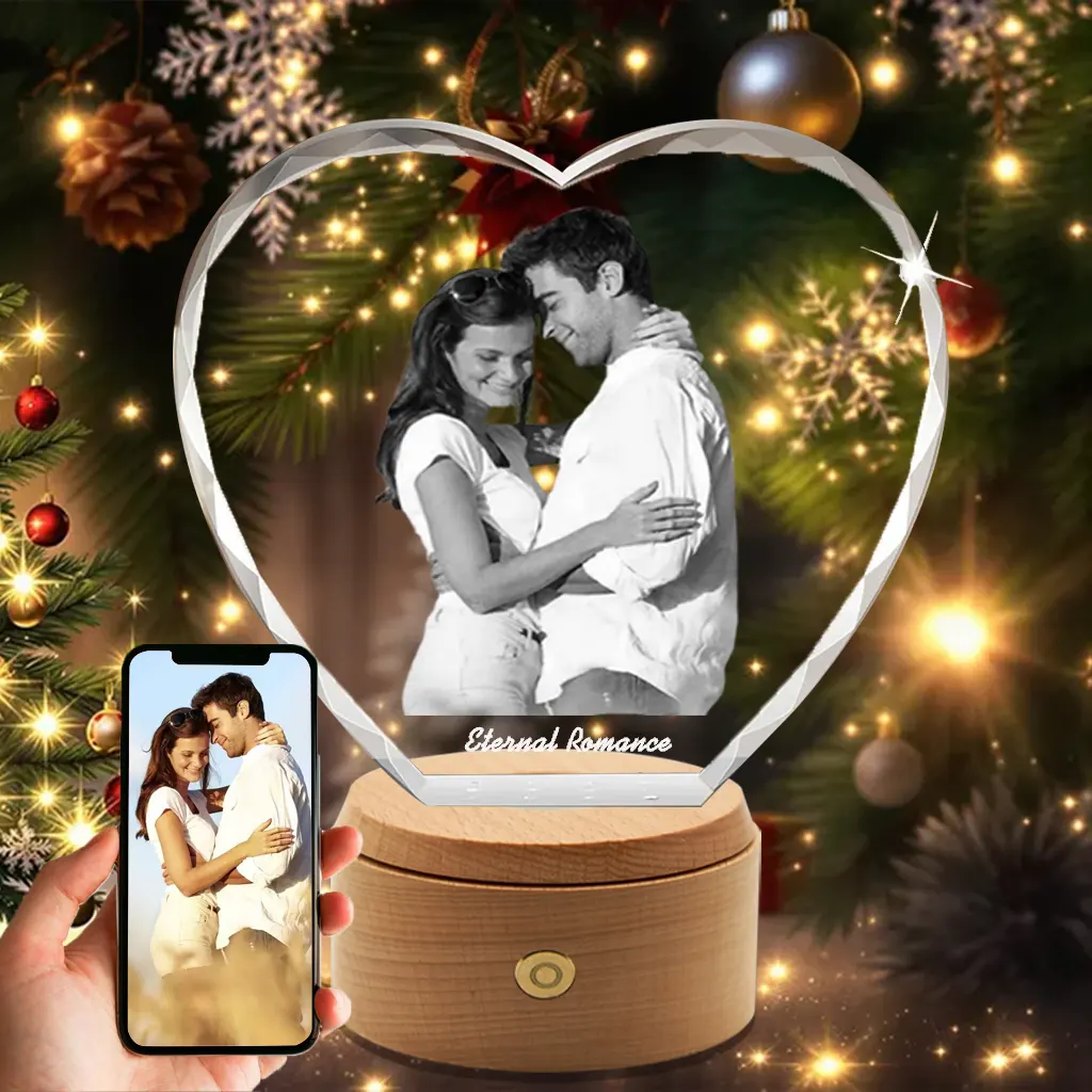 A diamond-cut heart-shaped 3D photo crystal, engraved with a romantic couple and "Eternal Romance," presented as a sparkling Christmas gift in front of a festive tree.