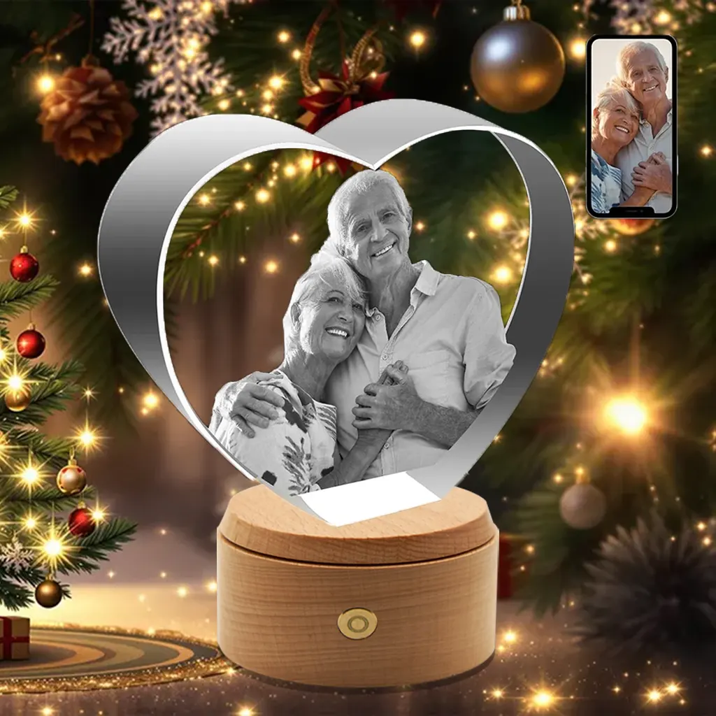 A heart-shaped 3D photo crystal engraved with a portrait of a loving elderly couple, presented as a sentimental Christmas gift in front of a festive tree.
