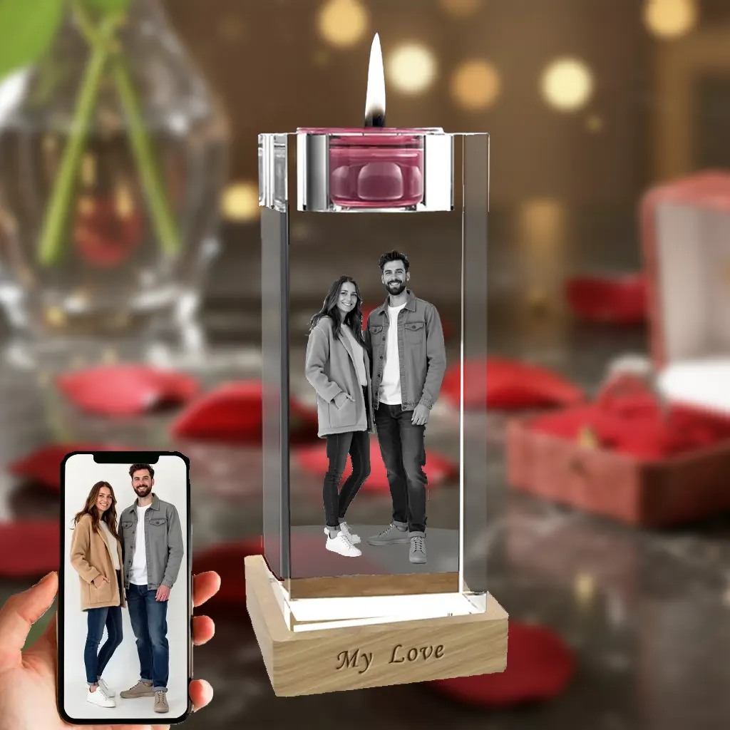 A tall, rectangular candlestick crystal internally engraved with a full-body portrait of a couple, topped with a lit candle. The crystal is placed on a wooden LED base engraved with 'My Love', against a romantic red rose background, with a phone in the bottom-left showing the original color photo.