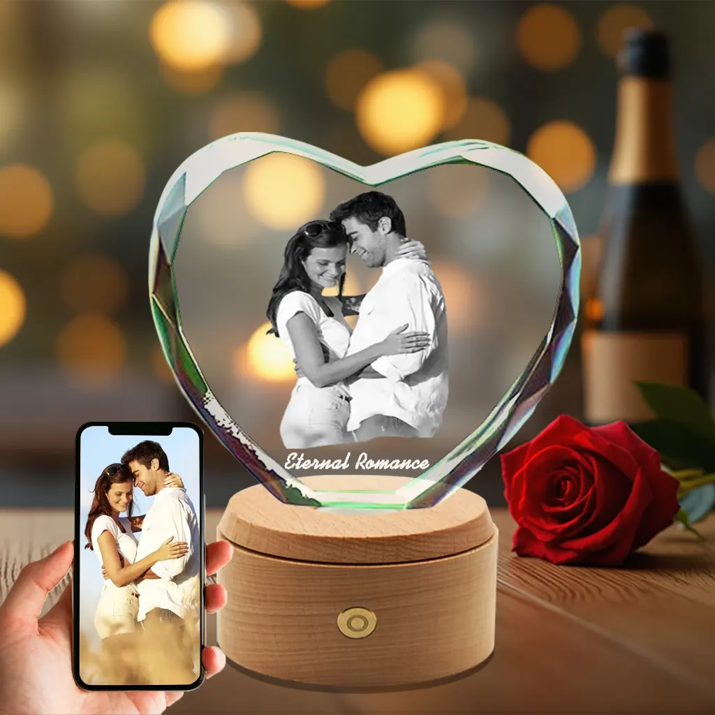 A diamond-cut heart-shaped 3D crystal engraved with a romantic photo of a young couple, displayed on an illuminated rotating wooden base, perfect as an anniversary gift.