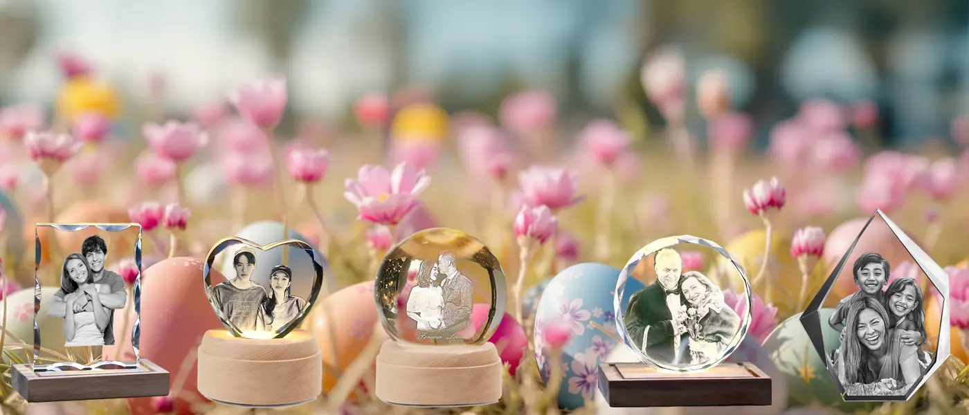A collection of personalized 3D photo crystal gifts in various shapes, beautifully arranged amidst a cheerful spring meadow filled with colorful Easter eggs and blooming pink flowers.