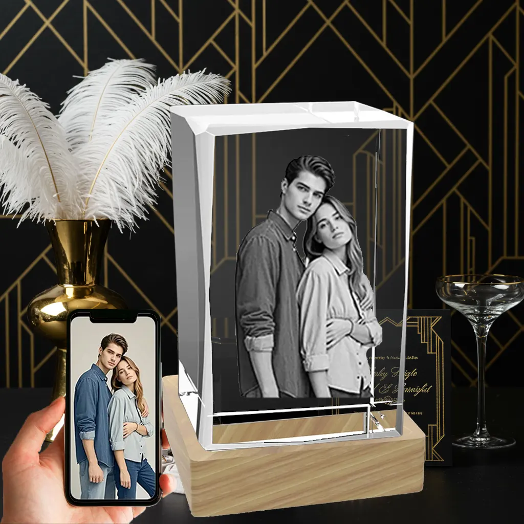 A 3D laser-etched photo of a couple hugging is inside a beveled rectangular crystal block, which sits on a light wood LED base. A hand holds a smartphone showing the original color photo, against an elegant art deco background.