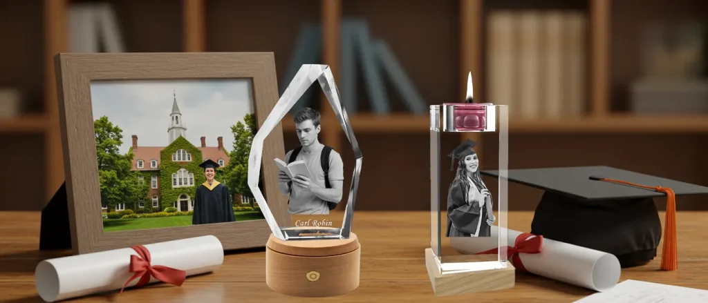 A commemorative display of personalized 3D photo crystal graduation gifts, set on a scholarly desk alongside a graduation cap, diplomas, and a university photo frame.