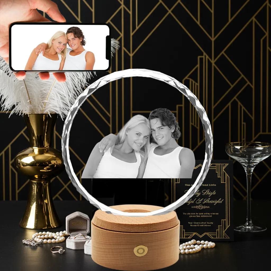 A 2D photo of a couple is engraved inside a round, faceted "sunflower" crystal, which sits on a wooden LED music box base. A hand holds a phone displaying the original color photo above it, against a black and gold art deco background.
