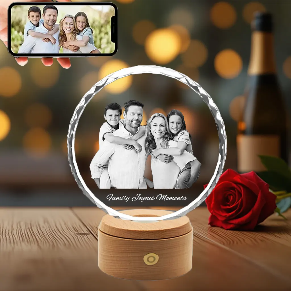 A round, sunflower-faceted 3D photo crystal engraved with a happy family of four and the text "Family Joyous Moments," displayed on an illuminated rotating wooden base.
