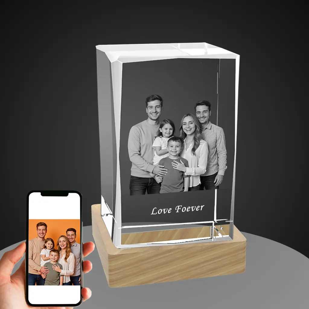 A YiYues personalized 3D rectangular crystal block featuring a custom 3D photo of a happy family, with 'Love Foever' engraved. A hand holds a smartphone showing the original color photo, demonstrating the customization.
