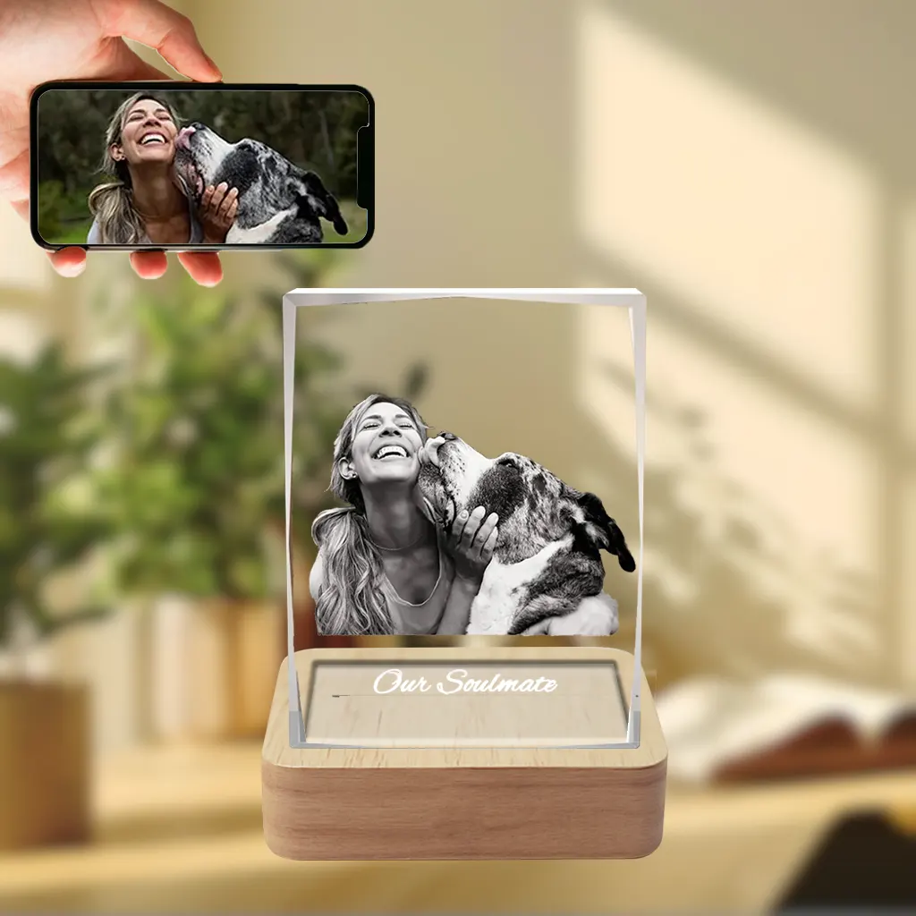 A YiYues personalized 3D Crystal Pillar featuring a heartwarming custom photo of a woman and her dog, with 'Our Soulmate' engraved, on a lighted wooden base. A smartphone displays the original source photo.