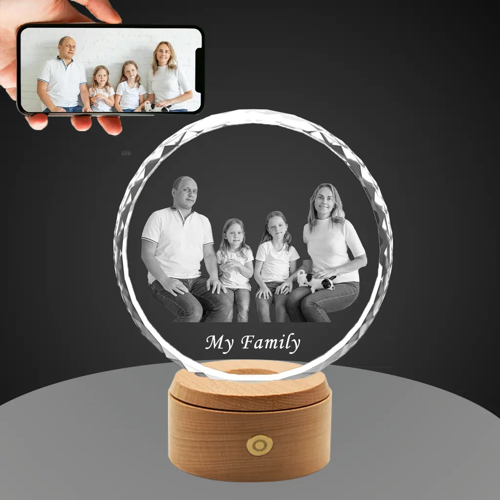 A YiYues personalized 3D Sunflower Crystal featuring a custom photo of a family of four, engraved with 'My Family', on a lighted wooden base. A smartphone shows the original color source photo.
